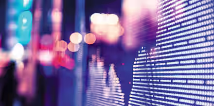 A close-up of an LED screen displays a financial graph with a cityscape in the background. The screen shows a series of dots forming line patterns, representing data. The scene is illuminated with blue and pink lights, giving it a futuristic feel.