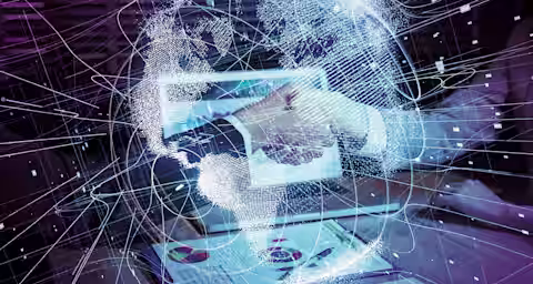 A futuristic image showing a person using a tablet. Surrounding the tablet and their hand are glowing, intricate digital lines and nodes forming a virtual network or globe, suggesting connectivity and advanced technology. A document with charts is on the table.