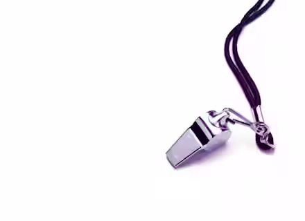 A shiny silver whistle attached to a black lanyard is positioned on a white background, with the lanyard coiled in loops next to the whistle.