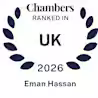 A blue laurel wreath surrounds the text: "Chambers Ranked In UK 2026" with the name "Eman Hassan" below, indicating a ranking recognition.
