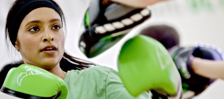 An image of a woman working out with boxing pads