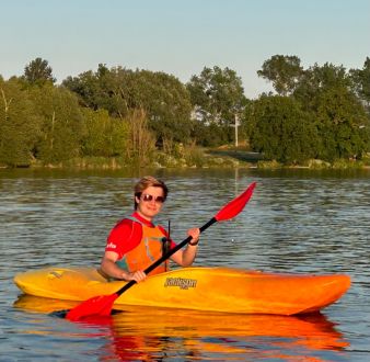 Young blond man in sunglasses paddling a yellow kayak on Stanborough Lake