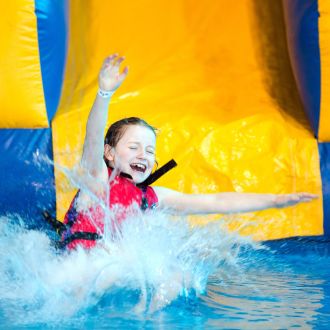 An image of a child sliding down a water inflatable slide