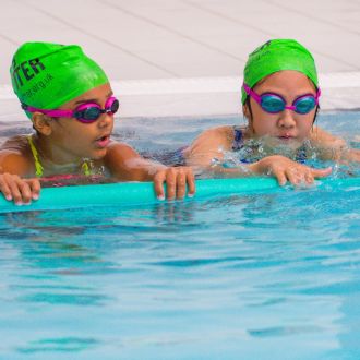 An image of two children holding onto floats in a swimming lesson