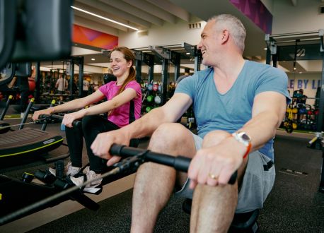 Father and daughter on rowing machines in a gym