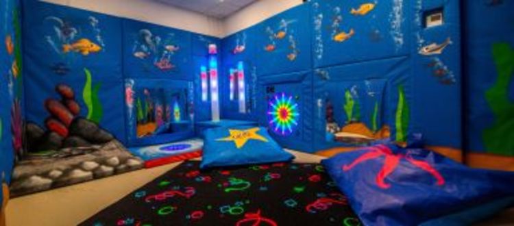 sensory soft play area, blue walls, bright colourful space, colour changing bubble tubes glowing.