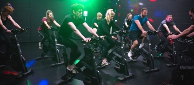 people on exercise bikes in a dark studio