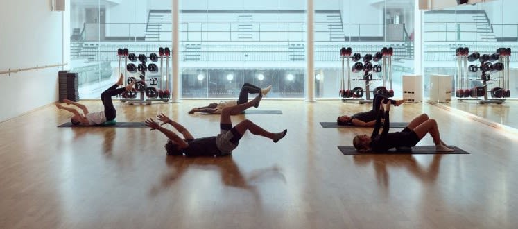 image shows a group of people laying in a dark studio space doing yoga exercises
