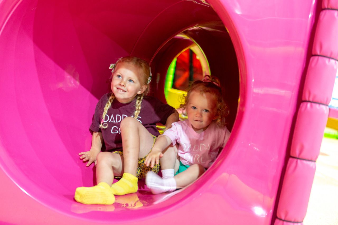 Two girls playing in a tunnel at soft play