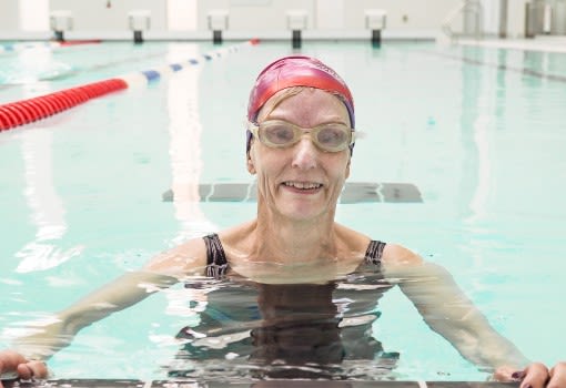 Better member swimming in a swimming pool with hat and goggles