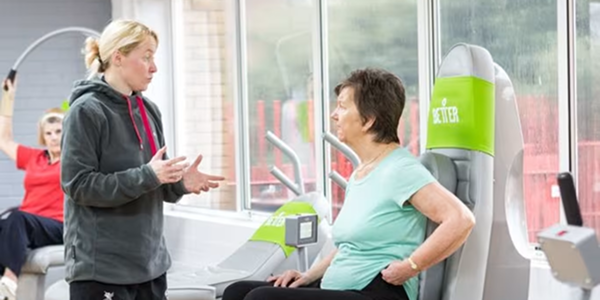A woman working out at the gym with a female instructor