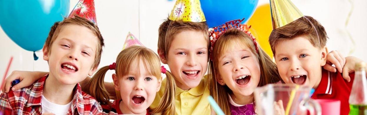 5 Children of various ages with Party hats on their head, linking arms and smiling.