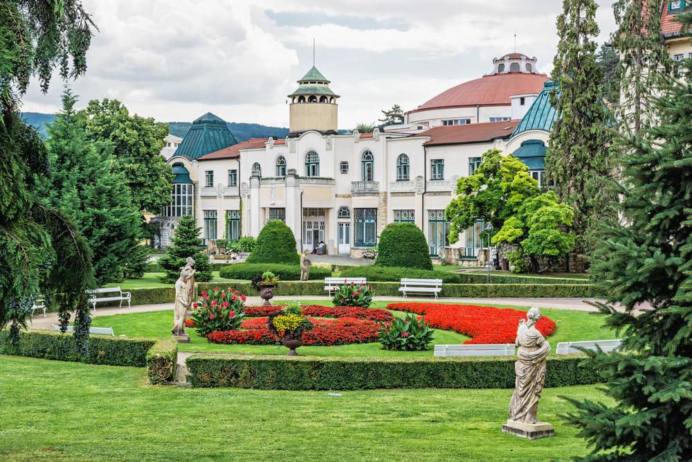 A Park with Flowerbeds in front of an Old White Building