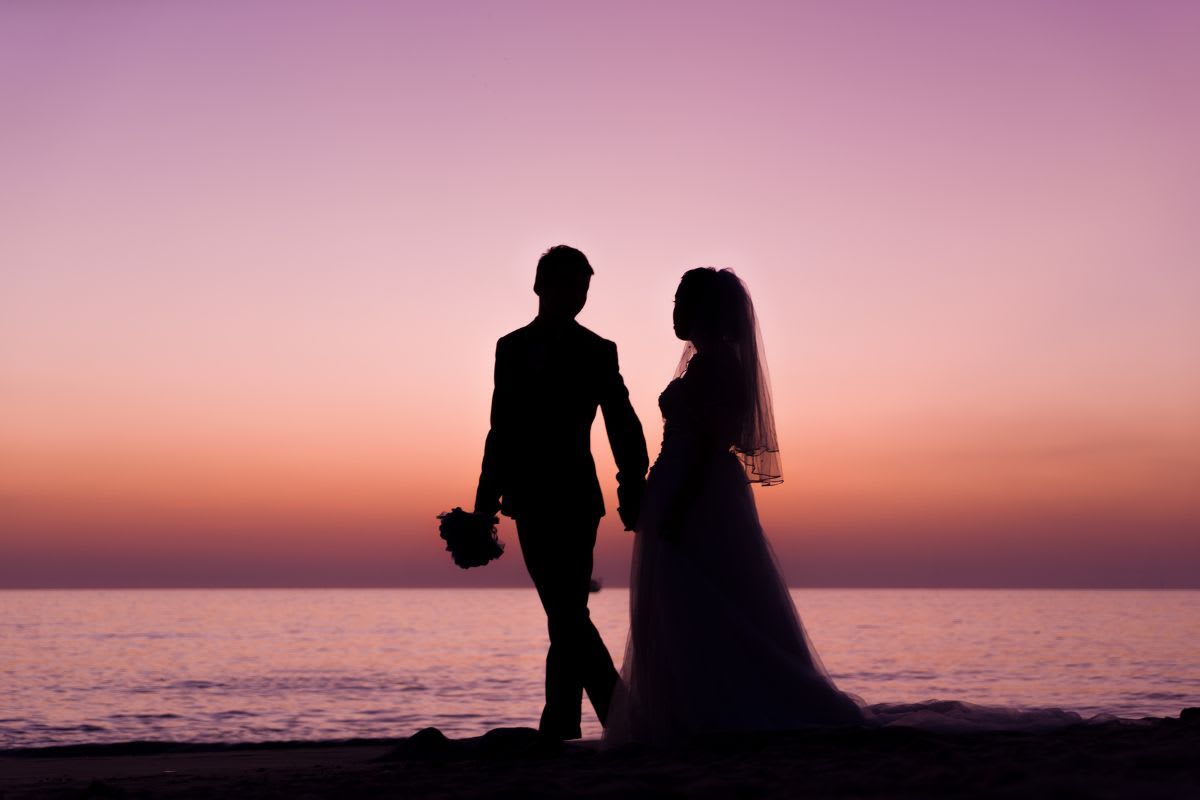 Brautpaar im Umriss vor einem malerischen Sonnenuntergang am Strand von Mallorca.
