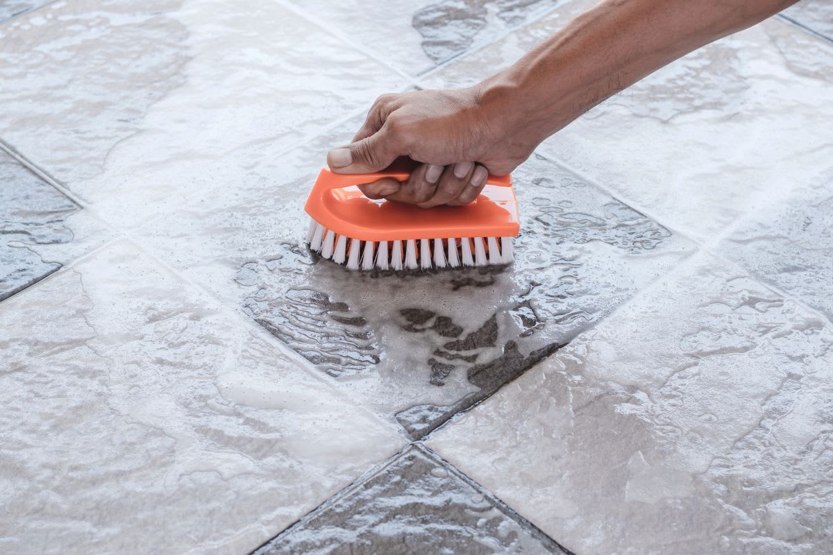 Sorgfältige Reinigung von Naturstein-Terrassenplatten mit einer Bürste und mildem Reinigungsmittel, um die natürliche Schönheit des Materials zu bewahren.