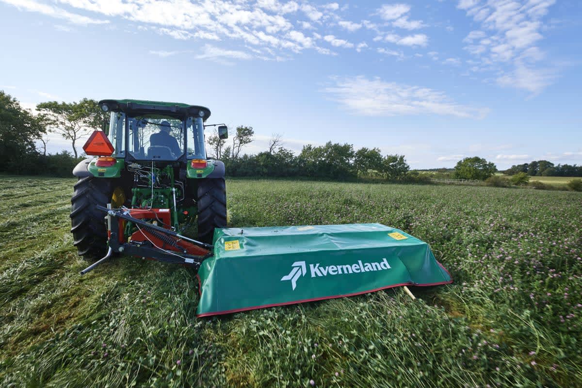Faucheuse Kverneland 2300M dans un champ de luzerne attelée à un tracteur de la marque Fendt