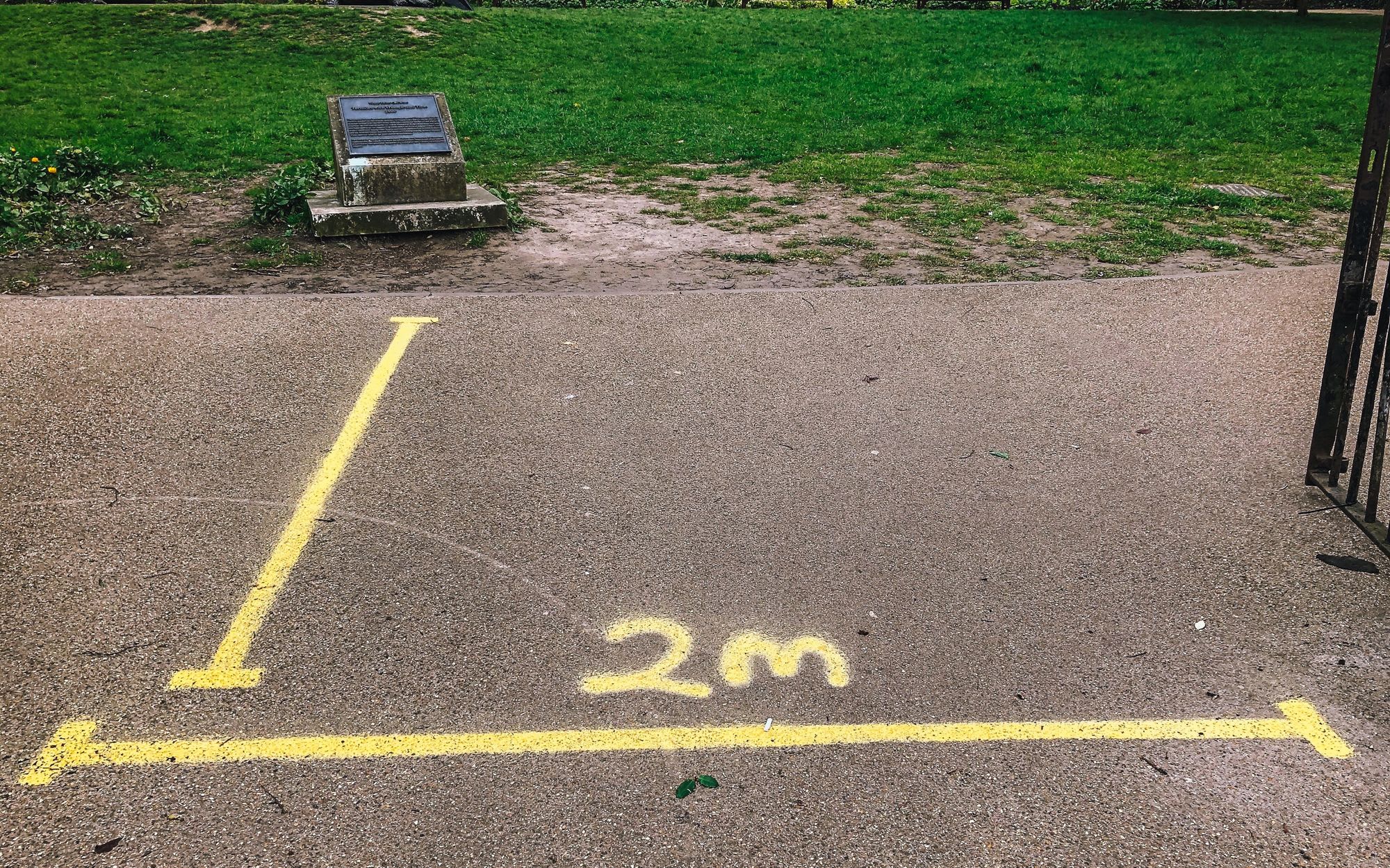 2 yellow lines and "2m" spray painted on the ground at the entrance of Holland Park