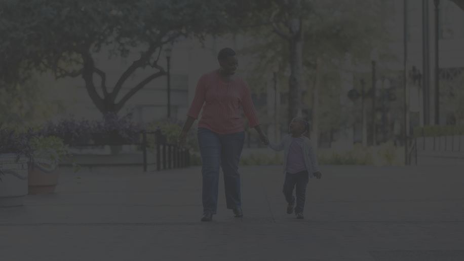 a middle aged Black woman and her young daughter go for a walk in a city