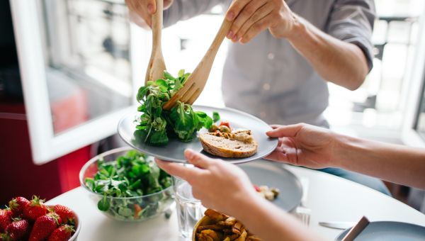 scooping salad onto a plate with tongs