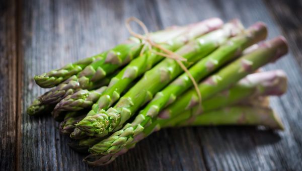 asparagus tied in a bundle on a wooden tabletop