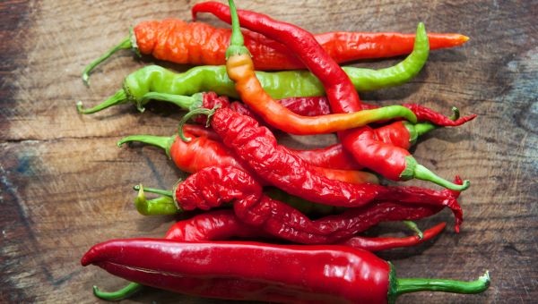 red peppers sitting on a dark brown wood table