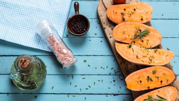 sweet potatoes, cutting board, spices, wooden table, oil