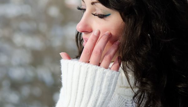 woman, white sweater, hand touching face