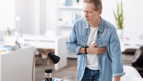 man holding chest, heart attack, living room