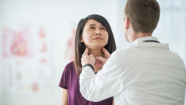 doctor checking patient's thyroid