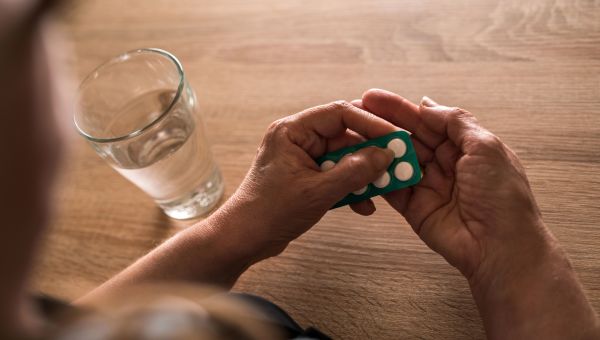 Woman taking white pills with water