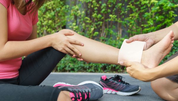 Person wrapping woman's injured ankle in bandage