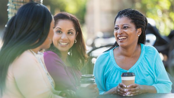 three people talking with paper takeout coffee cups in their hands