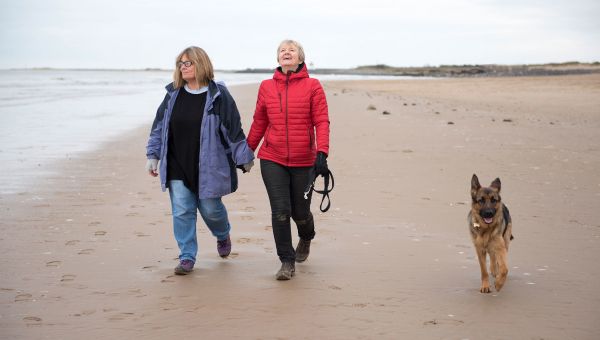 Lesbian couple walking their dog on the beach