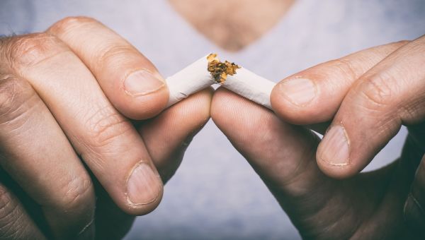 Person breaking a cigarette in half.