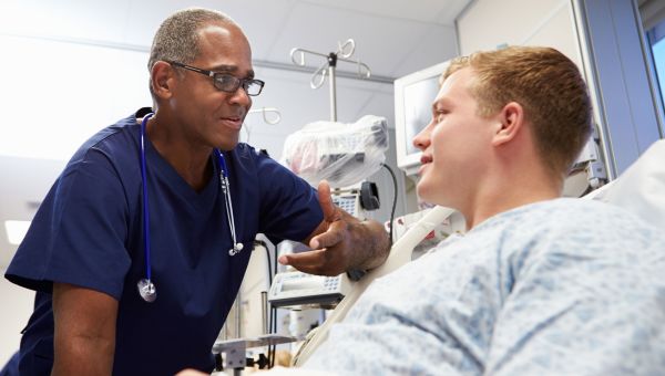 Patient in hospital bed talking to a nurse.