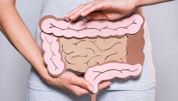 Woman holding a colon cartoon cut out over her stomach.