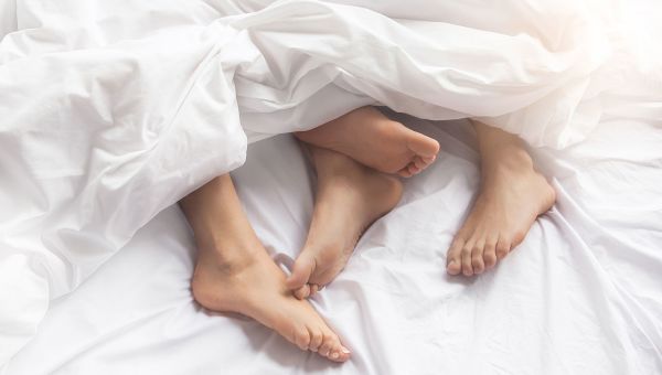 Couple in bed with their feet peeking out from the covers.