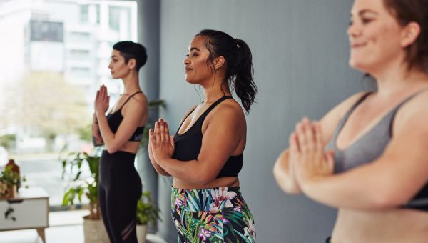 three young fit friends practice yoga