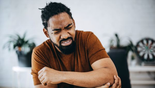 Female doctor talks to elderly patient about his knee pain.