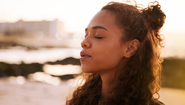 woman deep breathing meditating on beach