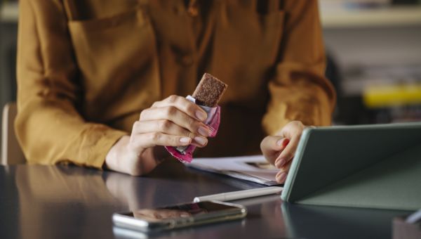 woman eating granola bar at desk