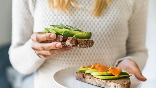 woman holding avocado toast with salmon lox