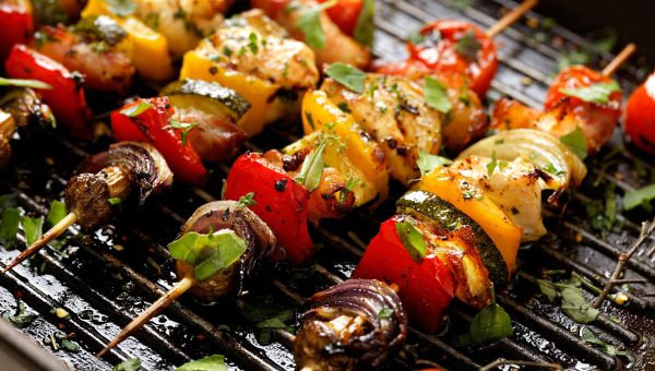 Paleo-friendly vegetable skewers cooking on a grill.
