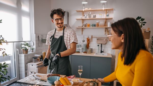 a young man and woman in a kitchen prepare food for a backyard barbecue