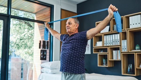 Older man holding resistance bands outstretched during an at-home workout.