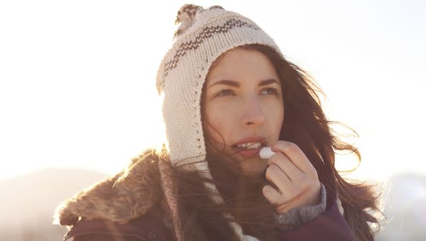 woman putting on chapstick to hydrate her lips during the wintertime