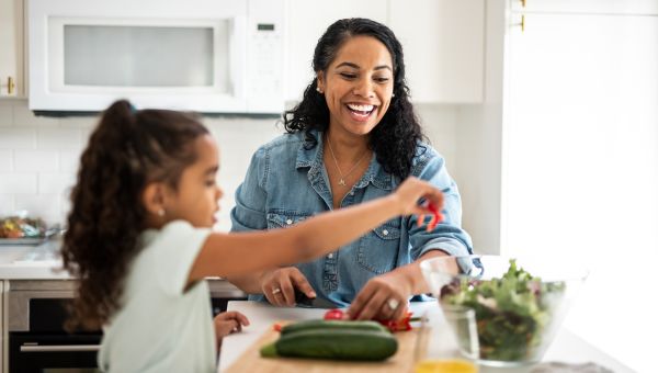 a woman and her daughter happily prepare fresh vegetables in a kitchen