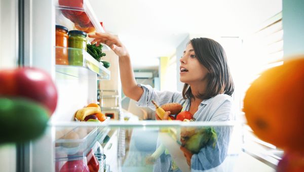 woman looking through open refrigerator