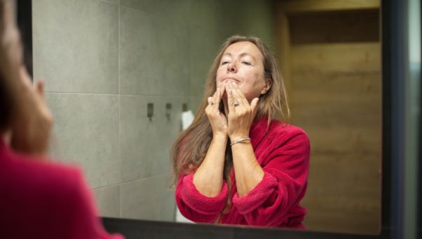 mature woman checking acne in mirror
