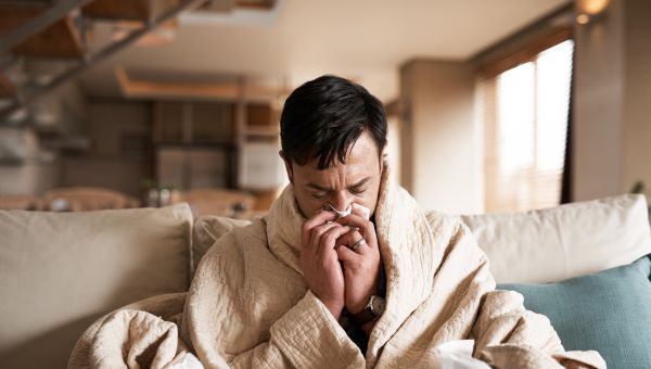 sick man on couch blowing nose